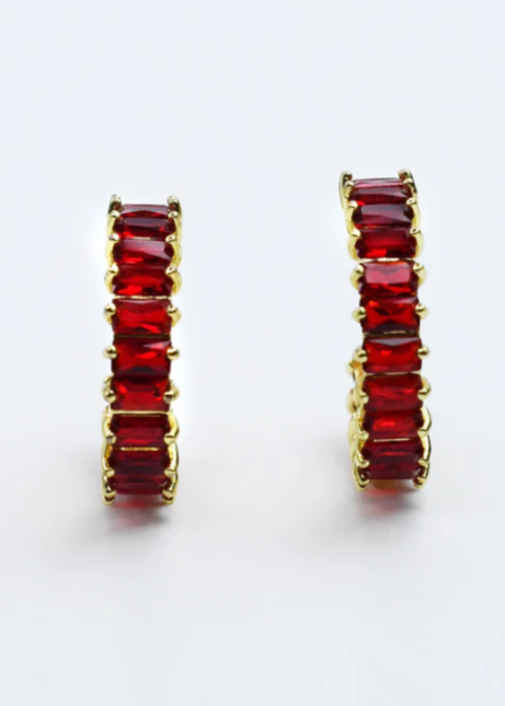 Pair of red gemstone earrings with gold setting on a white background