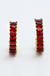 Pair of red gemstone earrings with gold setting on a white background