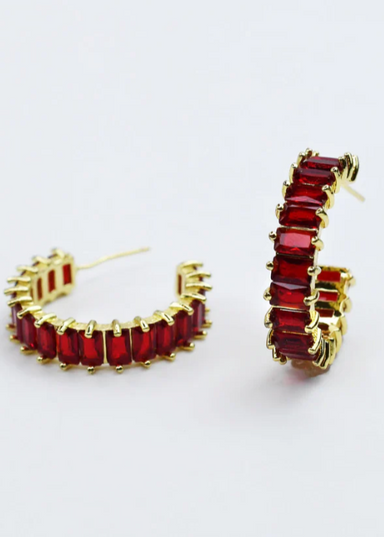 Gold hoop earrings with red gemstones on a white background