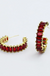 Gold hoop earrings with red gemstones on a white background